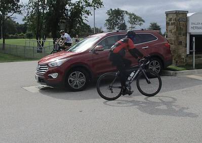 Bicycle delivery near a red SUV at Bluebonnet Express in Texas, highlighting eco-friendly transportation.