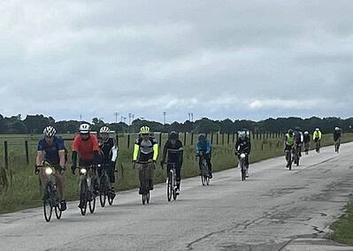 Group of cyclists riding on a rural road, practicing outdoor bike riding, and enjoying scenic views.