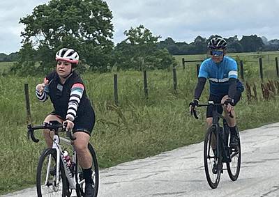 Riders cycling on rural road, enjoying scenic outdoor bike ride, professional biking gear, Bluebonnet Express style.