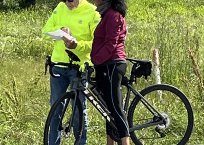 - Road cyclist and support team discussing route on scenic country road.
