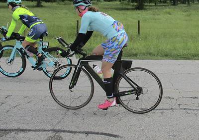 Brightly dressed cyclists riding on rural road in Texas during Bluebonnet season.