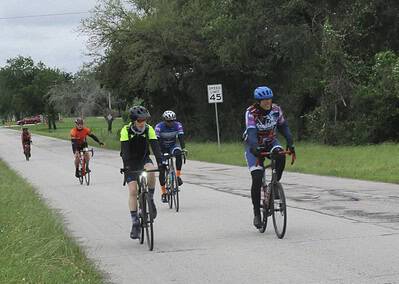 Vibrant cyclists enjoying outdoor ride on scenic bike trail with green trees and overcast sky.
