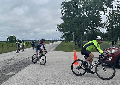 Cyclists riding on a rural road with bluebonnet express, showcasing scenic Texas bike routes.
