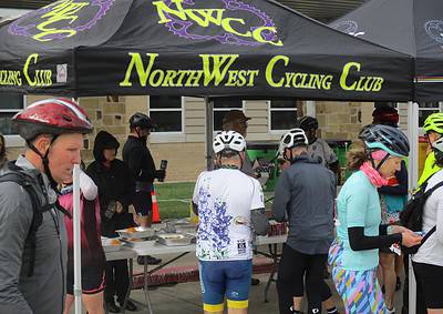 Cyclists enjoying snacks at NorthWest Cycling Club event under a branded canopy.