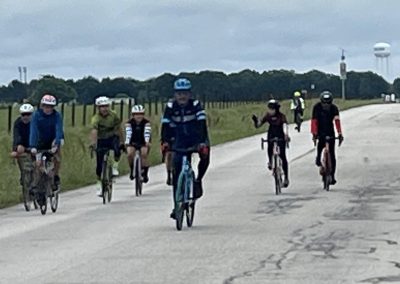 Cyclists riding on a scenic trail with bluebonnet flowers, outdoor recreation, and community biking event.