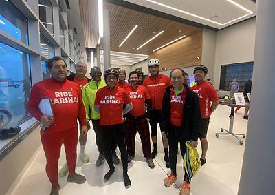 Cycling team group photo at Bluebonnet Express event, framed by modern indoor setting and large windows.