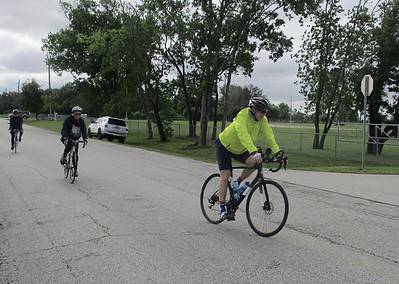 Vibrant cyclists enjoying outdoor ride on Bluebonnet Express bike trail in Texas, surrounded by lush greenery and overcast skies.