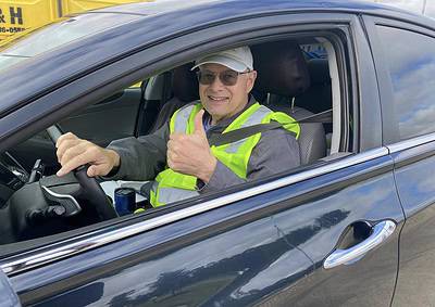 Happy delivery driver in the driver’s seat giving a thumbs-up inside a sleek black car.