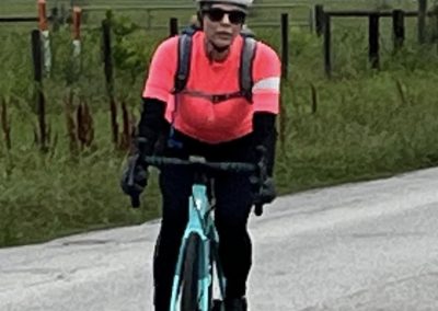 High-speed cyclist wearing pink jersey on rural road, promoting Bluebonnet Express bike services.