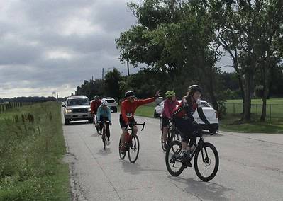 Bicyclists riding along a scenic route during the Bluebonnet Express event under cloudy skies.