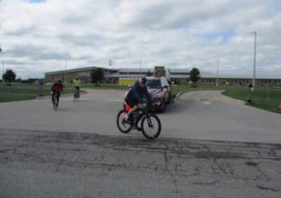 Bicycle rider near Bluebonnet Express school building on cloudy day.