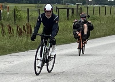 Cyclists riding along a scenic countryside road on a sunny day.