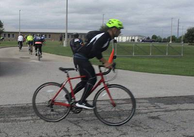 Cyclist riding a red bike with an orange safety cone in a bike race or event.