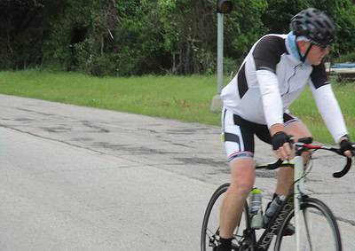 High-performance cyclist biking on a scenic road, emphasizing outdoor cycling and fitness.