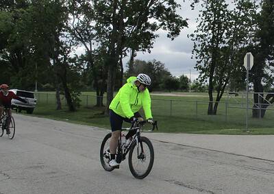 Bright neon yellow cycling jacket and helmet, scenic park background, associated with Bluebonnet Express biking event.
