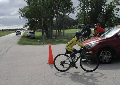 Children riding bikes around a traffic cone during a biking safety event.