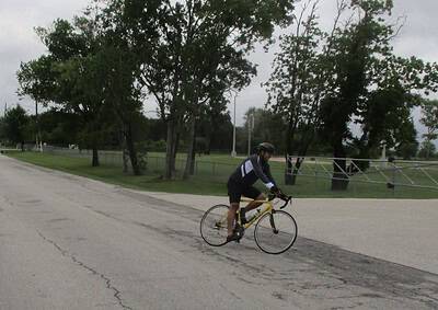 Cyclist riding on a paved trail with trees in the background, showcasing outdoor biking in Texas.