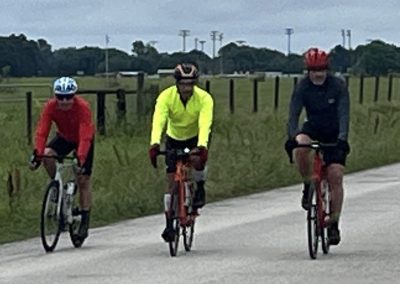 Colorful cyclists riding on a paved trail, wearing helmets and activewear for Bluebonnet Express event.