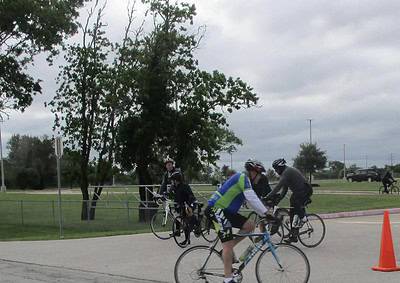 Cyclists riding near trees at Bluebonnet Express event on a cloudy day.