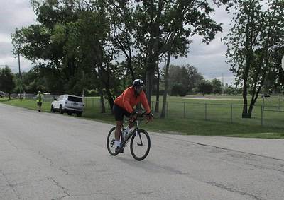 Cyclist riding on a scenic road with trees and park area, promoting Bluebonnet Express bike services.