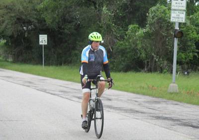 Comfortable cyclist riding with safety gear on a scenic road in Texas.