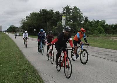 Bicycle group riding along a paved road during daytime, promoting cycling events and outdoor activities.