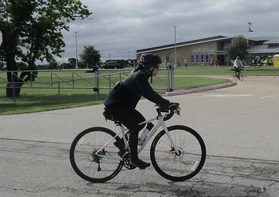 Bike riding at Bluebonnet Express event, outdoor cycling, cyclist in black gear, urban park scene, recreational biking, Texas bike event.