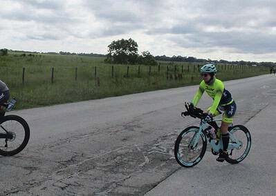 Biking on open road during Bluebonnet Express event with scenic rural landscape behind.