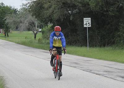 Cyclist riding downhill on a scenic rural road in the Bluebonnet Express event.