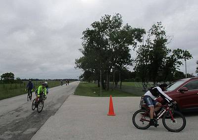 Brightly colored cyclists riding on rural bike trail during daytime.