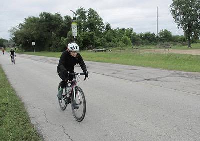 Cyclist riding along a rural road with Bluebonnet Express service visible in the background.