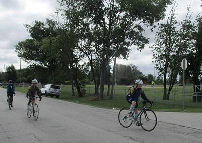Bright Bluebonnet Express cycling event with riders on scenic park road during cloudy day.