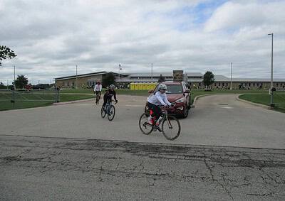 Biking event at Bluebonnet Express charity race outside a school building on a cloudy day.