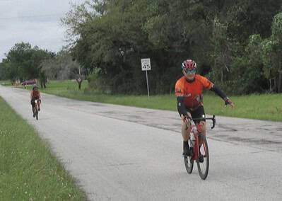 Vibrant cyclist riding on rural road with greenery, showcasing Bluebonnet Express bike event.