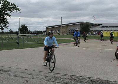 Cyclists enjoying a group ride outside Leander Middle School on a cloudy day.