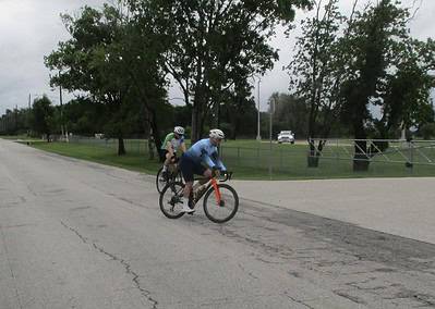 Cyclists riding on a scenic park road, enjoying outdoor biking and exercise.