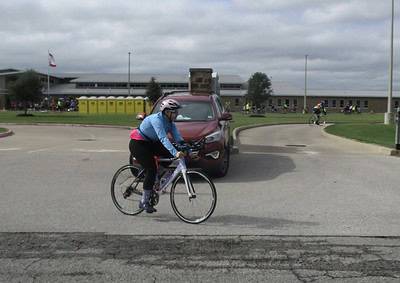 Cyclist riding a bicycle during Bluebonnet Express event at a school campus.