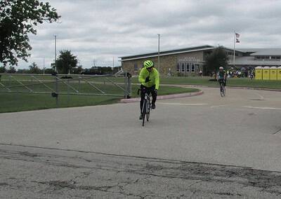 Cyclist in neon jacket riding near Bluebonnet Elementary School during daytime.