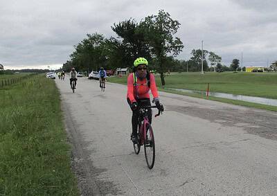 Rainbow-colored cycling woman on a mountain bike on a cloudy day.
