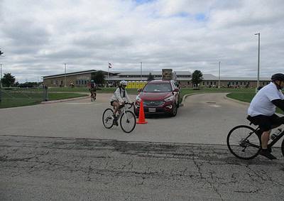 Biking activity at Bluebonnet Express school event on overcast day with students riding bikes near school entrance.