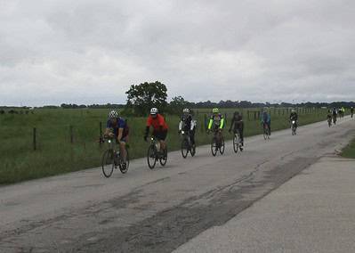Cyclists riding on a rural road during a group ride, showcasing Bluebonnet Express cycling event.
