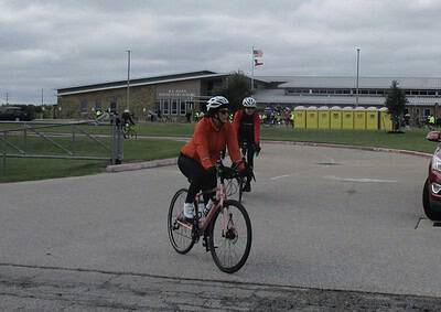 Cyclist riding towards Bluebonnet Express event at elementary school, outdoor cycling event in Texas.