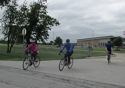 Cyclists riding bikes in a school zone during a community event, promoting healthy outdoor activities.
