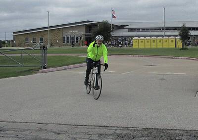 Bicycle rider in neon jacket at Bluebonnet Express event outside H.T. Jones Elementary School.