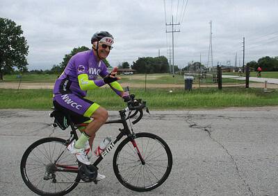 Bright cyclist riding on the road, wearing a purple NWCC jersey, celebrating at the Bluebonnet Express event.