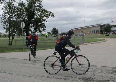 Bright cyclists riding on the street near Bluebonnet Express School bus stop.