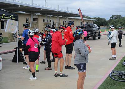 Cyclists gathering at Bluebonnet Express cycling event, preparing for the ride in a scenic outdoor setting.