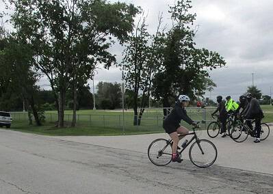Bicycle riders participating in a group ride event on a park road during daytime.
