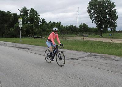 Cyclist riding on the road with scenic greenery in the background for Bluebonnet Express event.