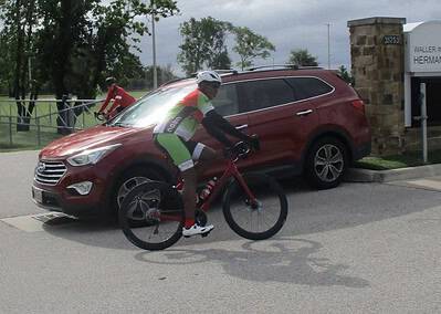 Cyclist riding past a red SUV near Hermann T. Jones Elementary School in Texas.